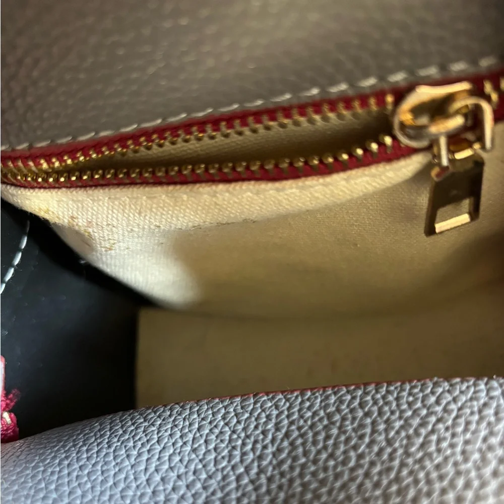 Small grey and maroon backpack with pocket in front and inside, cream interior